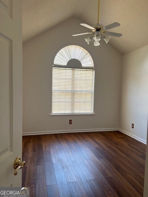 unfurnished room with ceiling fan, lofted ceiling, dark hardwood / wood-style floors, and a textured ceiling