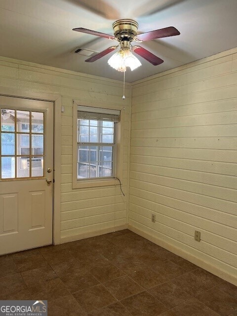 interior space featuring wooden walls and ceiling fan