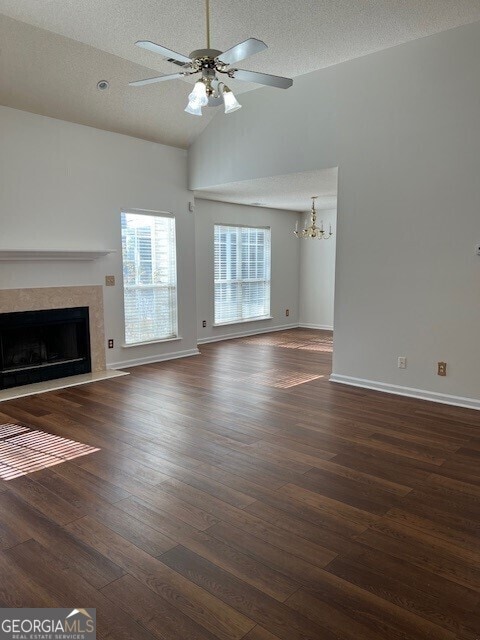 unfurnished living room with vaulted ceiling, ceiling fan, a premium fireplace, dark wood-type flooring, and a textured ceiling