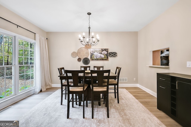 dining area with a healthy amount of sunlight, an inviting chandelier, and light hardwood / wood-style flooring