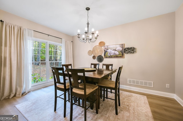 dining room with a healthy amount of sunlight, wood-type flooring, and a chandelier