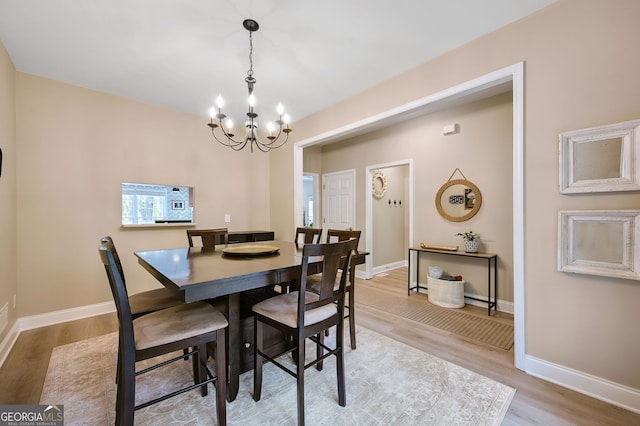 dining area with a notable chandelier and light hardwood / wood-style flooring