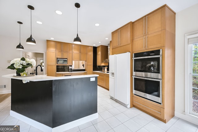 kitchen featuring hanging light fixtures, light tile patterned floors, a center island with sink, and appliances with stainless steel finishes