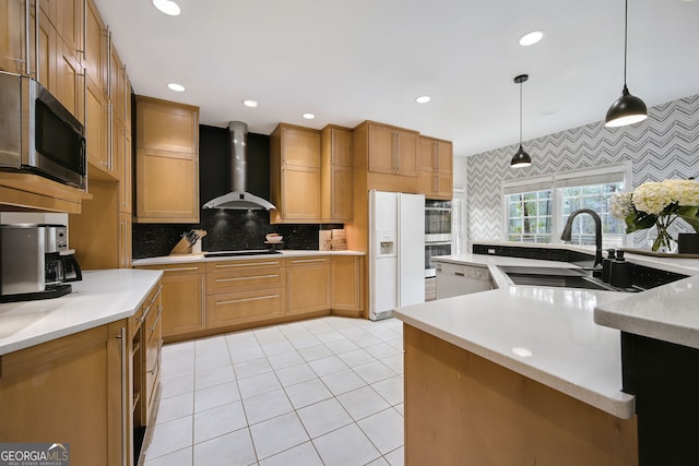 kitchen featuring pendant lighting, wall chimney range hood, white appliances, sink, and decorative backsplash