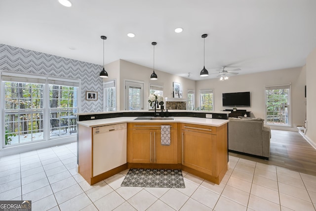 kitchen with hanging light fixtures, dishwasher, a kitchen island with sink, and light tile patterned flooring