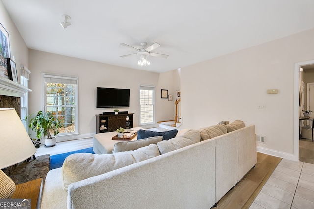 tiled living room featuring a fireplace and ceiling fan