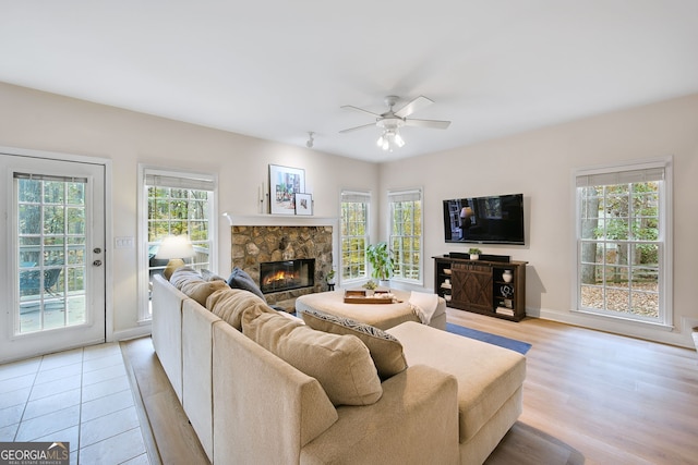 living room with ceiling fan, a healthy amount of sunlight, a fireplace, and light hardwood / wood-style flooring