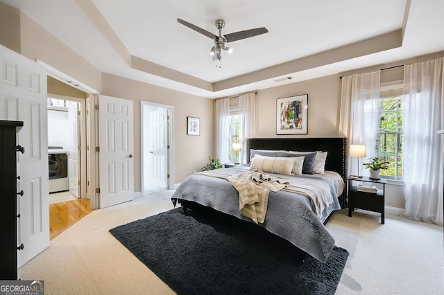 carpeted bedroom featuring a raised ceiling, ceiling fan, and washer / clothes dryer