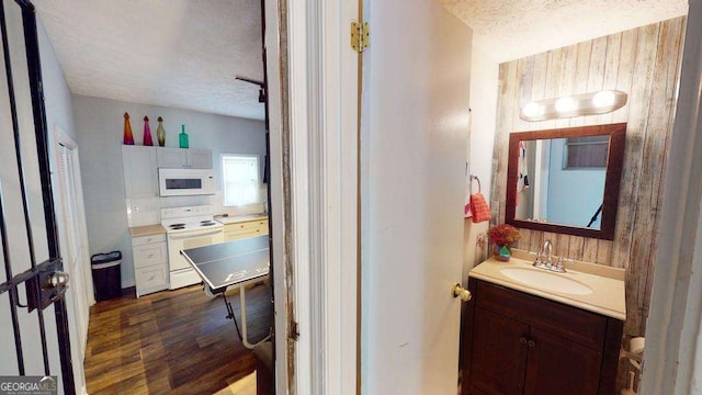 bathroom featuring vanity, hardwood / wood-style flooring, a textured ceiling, and wood walls