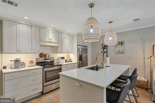 kitchen featuring sink, a breakfast bar area, appliances with stainless steel finishes, a kitchen island with sink, and hanging light fixtures