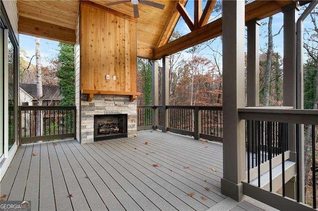 wooden terrace featuring ceiling fan and an outdoor stone fireplace