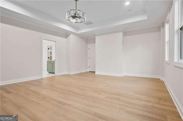 unfurnished room with a raised ceiling and light hardwood / wood-style flooring