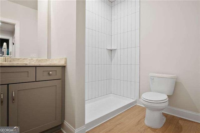 bathroom with wood-type flooring, walk in shower, vanity, and toilet