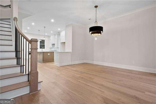 unfurnished living room with crown molding and light wood-type flooring