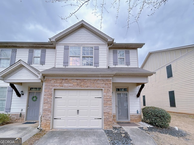 view of property featuring stone siding, concrete driveway, and an attached garage