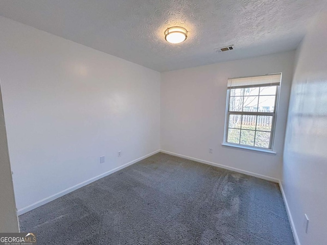 unfurnished room with visible vents, carpet flooring, a textured ceiling, and baseboards