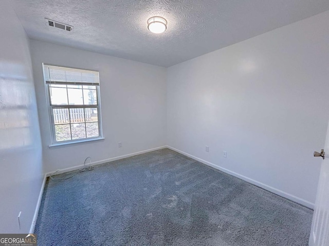 unfurnished room with visible vents, a textured ceiling, baseboards, and carpet