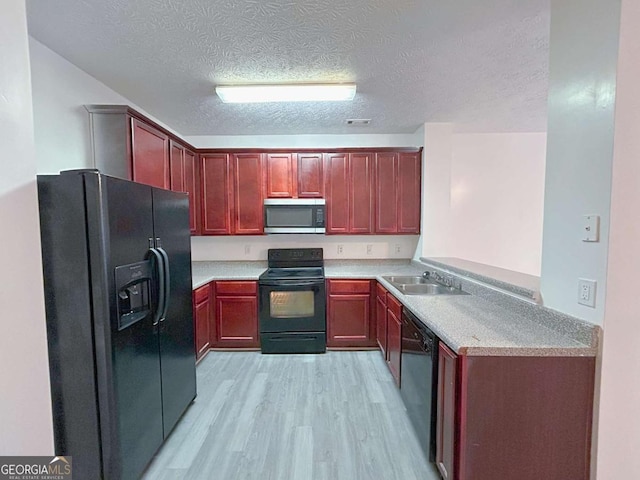 kitchen with light wood finished floors, a sink, light countertops, black appliances, and reddish brown cabinets