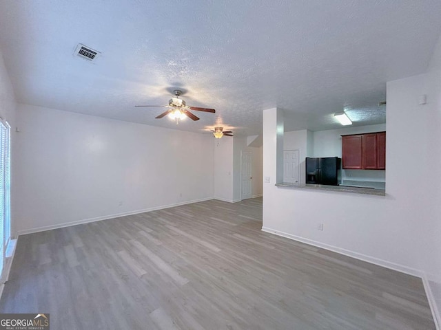 unfurnished living room with visible vents, light wood-style floors, a ceiling fan, and a textured ceiling