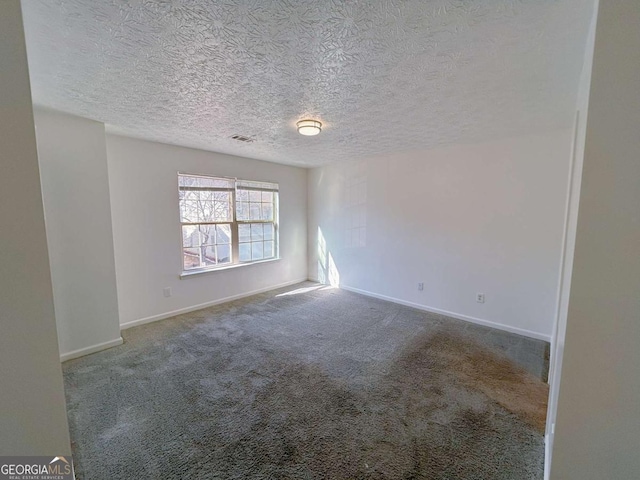 carpeted spare room featuring visible vents, baseboards, and a textured ceiling