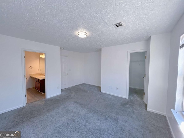 unfurnished bedroom with visible vents, carpet flooring, a walk in closet, and baseboards