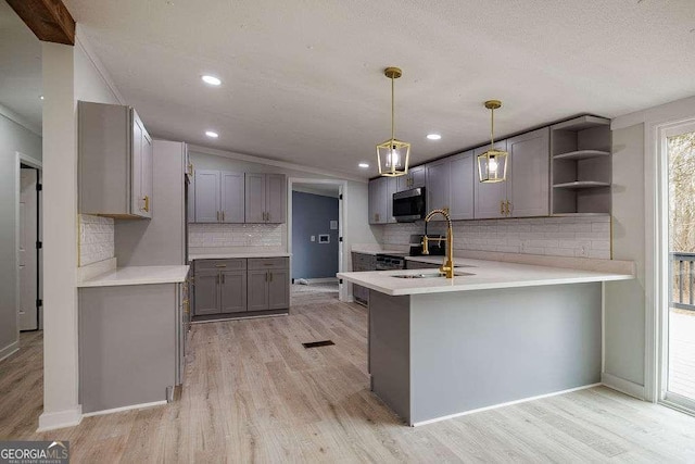 kitchen featuring sink, gray cabinets, kitchen peninsula, pendant lighting, and light hardwood / wood-style floors