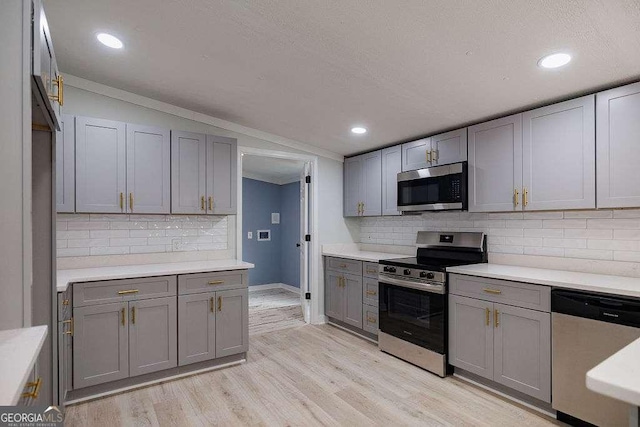 kitchen with lofted ceiling, appliances with stainless steel finishes, gray cabinets, and light hardwood / wood-style flooring