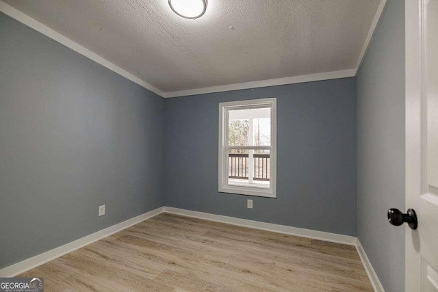 spare room with vaulted ceiling, ornamental molding, a textured ceiling, and light wood-type flooring