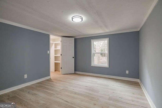 unfurnished room featuring ornamental molding, a textured ceiling, and light wood-type flooring