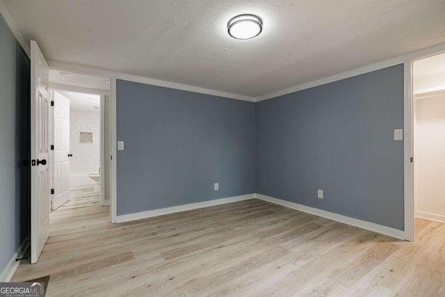 unfurnished room with crown molding, a textured ceiling, and light hardwood / wood-style flooring