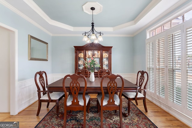 dining space with a notable chandelier, light hardwood / wood-style flooring, a raised ceiling, and plenty of natural light