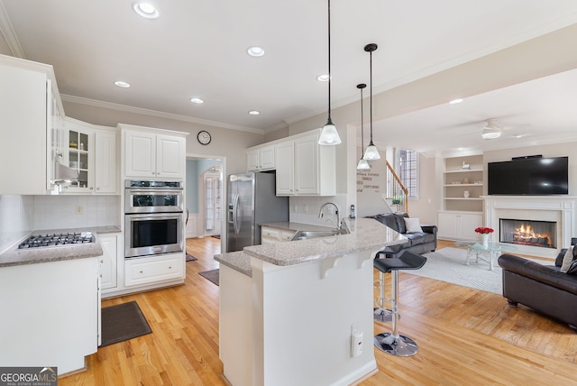 kitchen with sink, white cabinetry, decorative light fixtures, kitchen peninsula, and stainless steel appliances