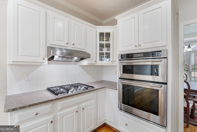 kitchen with backsplash, white cabinets, and appliances with stainless steel finishes