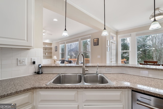 kitchen featuring white cabinetry, sink, ornamental molding, and decorative light fixtures