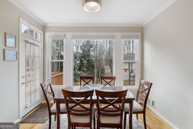 dining space featuring crown molding and light hardwood / wood-style flooring