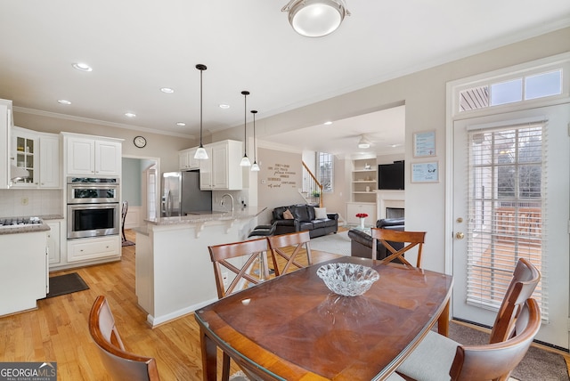 dining room featuring light hardwood / wood-style flooring, a wealth of natural light, ornamental molding, and ceiling fan