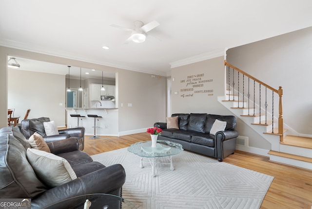 living room featuring crown molding, ceiling fan, and light hardwood / wood-style floors