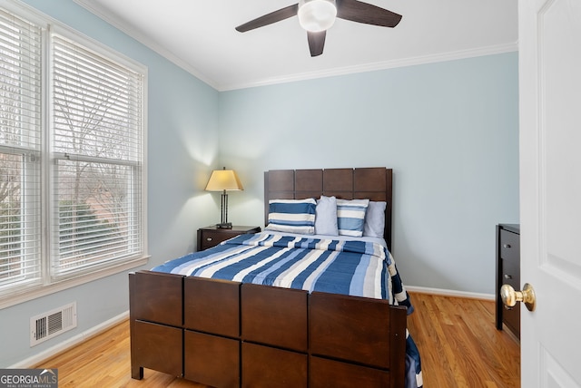 bedroom with ornamental molding, ceiling fan, and light hardwood / wood-style flooring