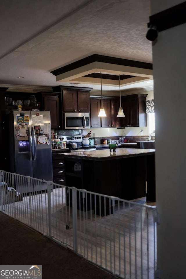 kitchen with appliances with stainless steel finishes, hanging light fixtures, dark brown cabinetry, a raised ceiling, and a textured ceiling