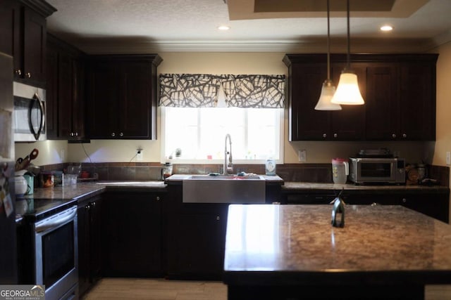 kitchen with crown molding, appliances with stainless steel finishes, dark stone countertops, dark brown cabinets, and decorative light fixtures