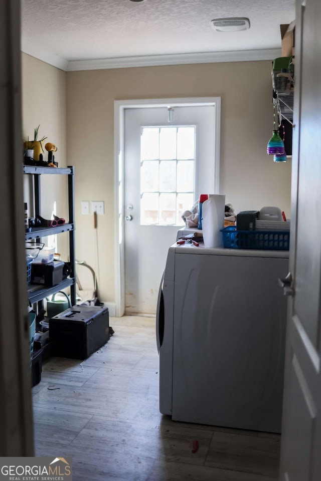 clothes washing area featuring crown molding, washer / dryer, and a textured ceiling