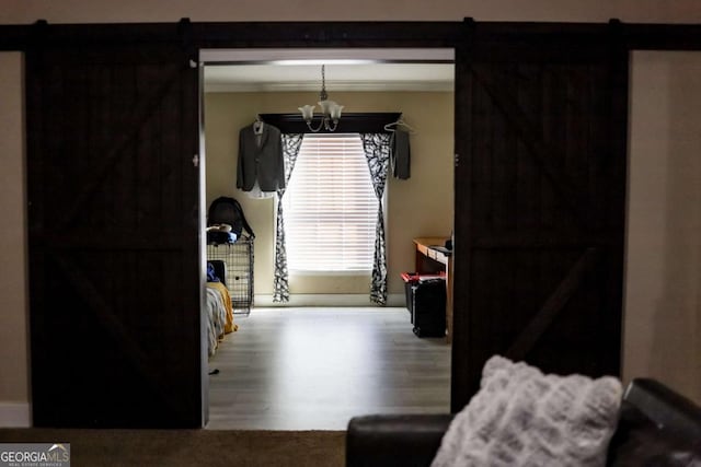 interior space featuring hardwood / wood-style flooring, a barn door, and a notable chandelier