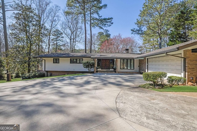 single story home featuring a garage, brick siding, and driveway