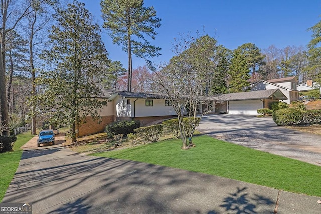 view of front of home featuring an attached garage, brick siding, concrete driveway, stucco siding, and a front yard