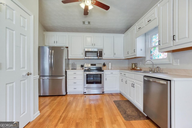 kitchen featuring white cabinetry, sink, stainless steel appliances, and a textured ceiling