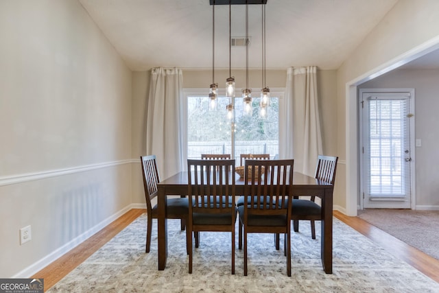 dining space featuring vaulted ceiling and light wood-type flooring