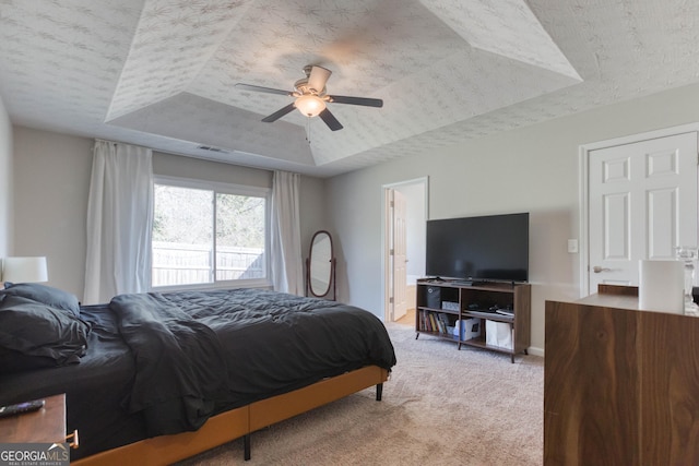 carpeted bedroom featuring connected bathroom, a raised ceiling, and ceiling fan