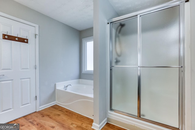 bathroom featuring a textured ceiling, wood-type flooring, and separate shower and tub