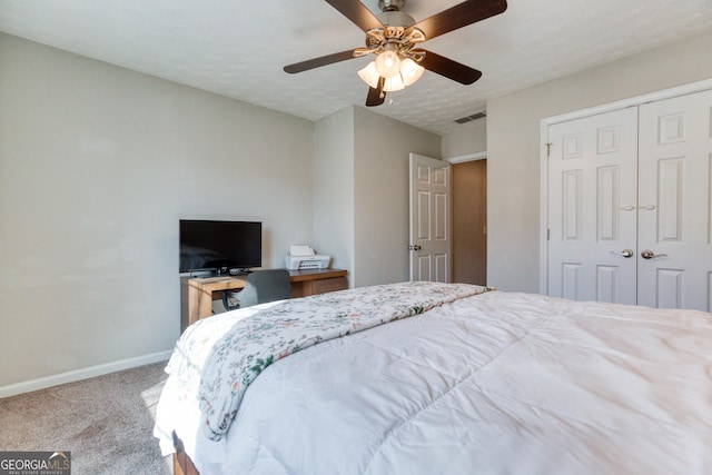 bedroom featuring a textured ceiling, light colored carpet, a closet, and ceiling fan