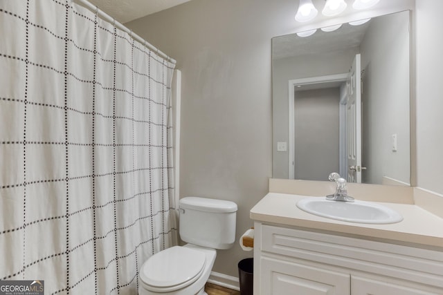 bathroom with walk in shower, vanity, and toilet